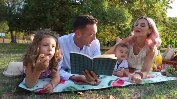 Μια Οικογένεια Κατά Διάρκεια Πικ Νικ Δημόσιο Πάρκο Γονείς Διαβάζουν — Αρχείο Βίντεο