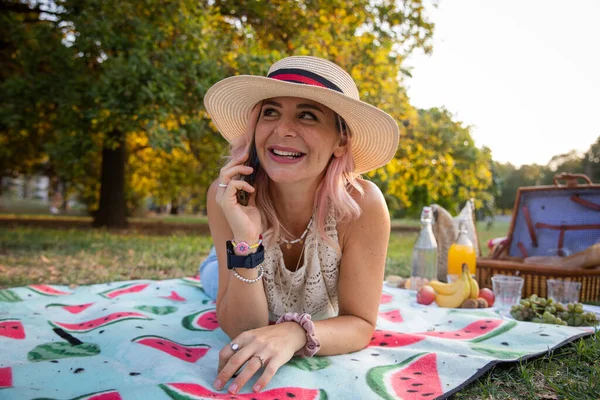 Beautiful smiling young woman during picnic enjoys making phone calls.