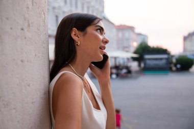 Şehir merkezinde bir direğe yaslanmış genç esmer bir telefon görüşmesi yapıyor..