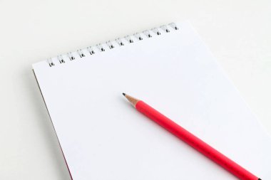 Pembe kalem beyaz bir not defterinin üzerinde yatıyor.