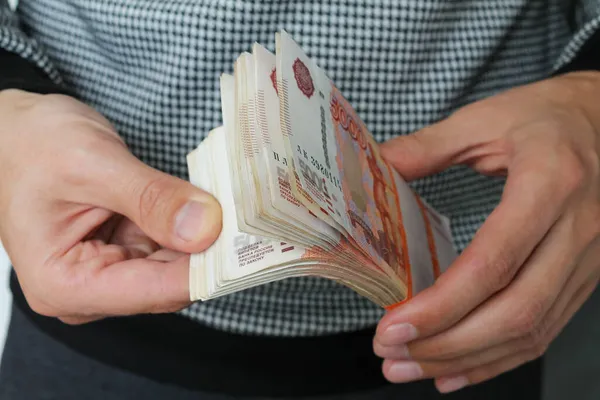 Κοντινά χέρια κρατούν ένα μάτσο ρωσικά χρήματα πέντε χιλιάδες χαρτονομίσματα.. Royalty Free Εικόνες Αρχείου