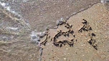 Kumun üzerindeki 2021 yazısını deniz dalgası silmiş. Mutlu yıllar 2022 konsepti.