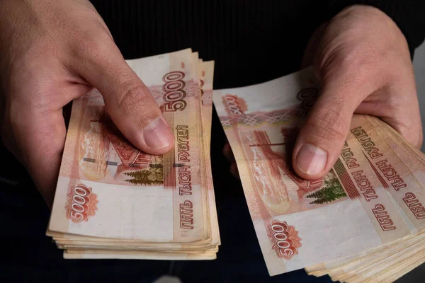 Руки человека крупным планом считают связку русских денег пятью тысячами купюр.. — стоковое фото