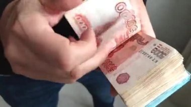 Bir adam elinde bir tomar para tutuyor. Bir adamın eli beş bin ruble 'lik banknotları sayar..