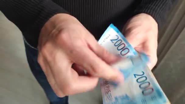 Mężczyzna trzyma w rękach kupę forsy. Zbliżenie męskich rąk liczy wiązkę banknotów za dwa tysiące rosyjskich rubli.. — Wideo stockowe