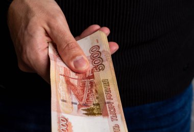 Bir adam beş bin dolarlık banknotlarla bir tomar Rus parası veriyor..