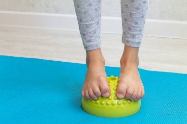 Çocuk ayak valginden yeşil dengeleyiciye egzersiz yapıyor. Childs 'ın bacakları yakın plan. Çocuklar için fizik tedavi dersleri