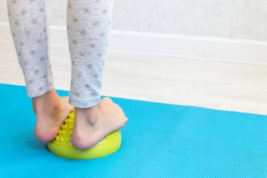 Çocuk ayak valginden yeşil dengeleyiciye egzersiz yapıyor. Childs 'ın bacakları yakın plan. Çocuklar için fizik tedavi dersleri