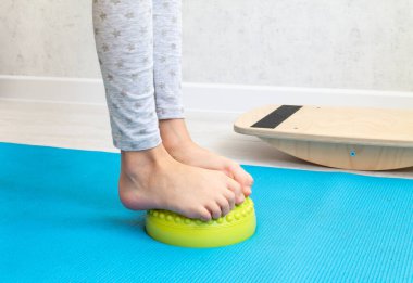 Çocuk ayak valginden yeşil dengeleyiciye egzersiz yapıyor. Childs 'ın bacakları yakın plan. Çocuklar için fizik tedavi dersleri