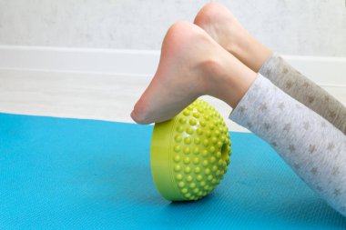 Çocuk ayak deformasyonundan dolayı dengeleyici ile egzersiz yapıyor. Bebek bacakları yakın. Çocuklar için fizik tedavi dersleri. Ayak masajı