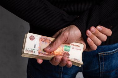 Adamların eli, arkalarında beş bin banknotla Rus parasından bir tomar tutuyor. Yolsuzluk, rüşvet.
