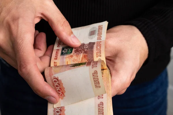 Руки человека крупным планом считают связку русских денег пятью тысячами купюр.. — стоковое фото