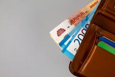 Üzerinde Rus parası olan cüzdan gri bir arka planda yatıyor.