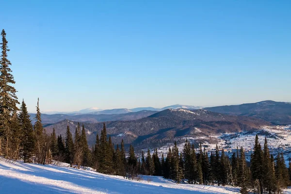 Winter landscape with snow falling, trees in snow and blue sky. Sheregesh ski resort in Russia, located in Mountain Shoriya, Siberia, aerial top view. — Stockfoto