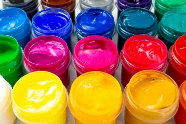 Open jars with gouache of different colors close-up. Hobby - painting.
