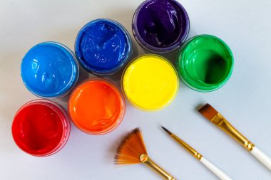 Gri arka planda farklı renkte gagalı ve fırçalı kavanozlar. Hobi - çizim. Üst görünüm