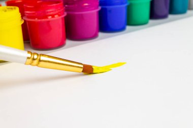 Bir çocuk beyaz bir çarşafa sarı boya çizer.