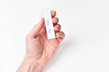 Covid 19 'un pozitif sonucu. Hızlı antijen kullanımı, erkeğin elinde. Beyaz arka planda yakın plan görüntüsü.. 