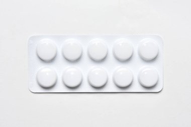 Haplar beyaz arka planda paket üst görünümde. İlaç tableti su toplayan kabın içinde.