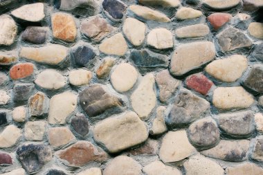 Yuvarlak kayaların duvar dokusu tuğla zemin. Kaba kesilmiş taş duvarlar yığılmış..