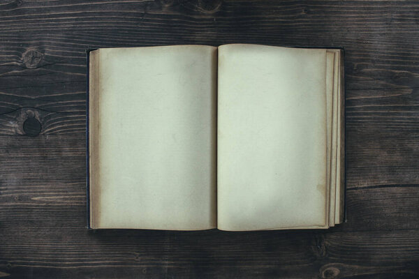 Open book with blank pages on a wooden table. Mockup of an old book on a table top view.