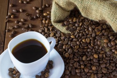 Sütlü kahve ve ahşap zeminde çuval bezeli kahve fincanı.