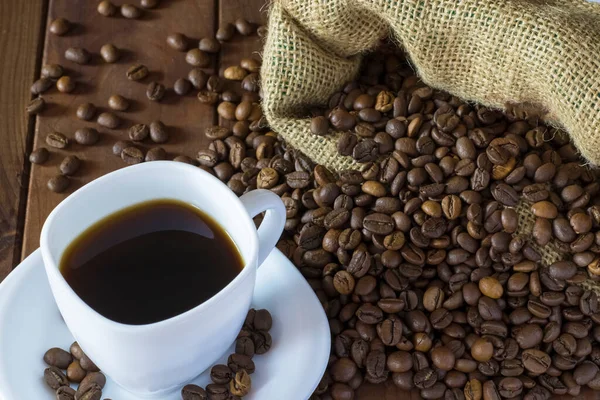 Sütlü kahve ve ahşap zeminde çuval bezeli kahve fincanı.