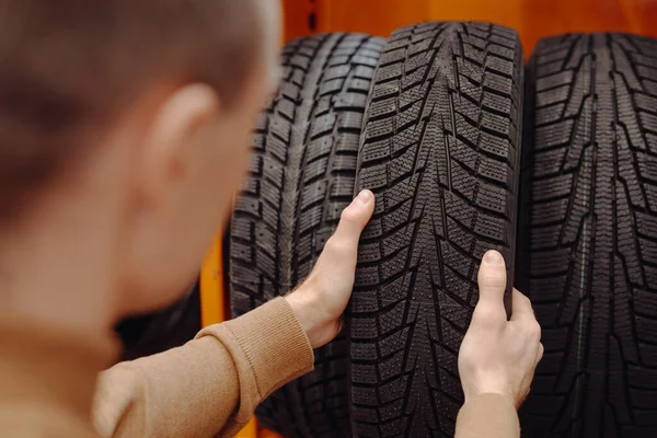 Hombre irreconocible elige neumáticos de coche de invierno en un taller de automóviles —  Fotos de Stock