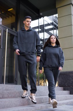 Şık bir çift binanın merdivenlerinden aşağı iniyor.