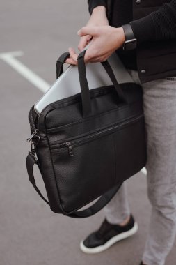 Adam dizüstü bilgisayarı çantaya koyar