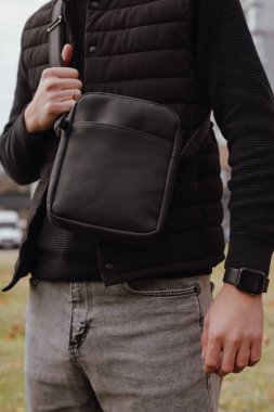 Yakından tanınmayan bir adam şehirde kurye çantası tutuyor.