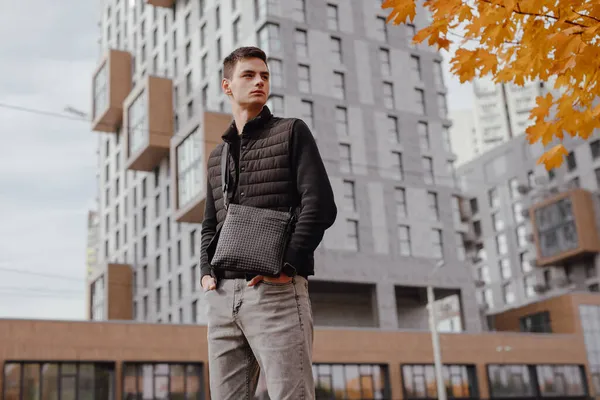 Man holding messenger bag in an autumn city — Stock Photo, Image