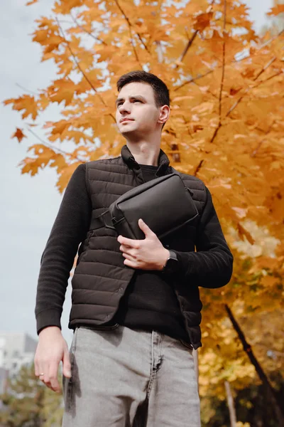 Чоловік тримає сумку в осінньому парку — стокове фото