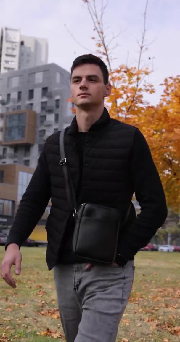 Férfi séta futár táska egy őszi város, függőleges videó — Stock videók