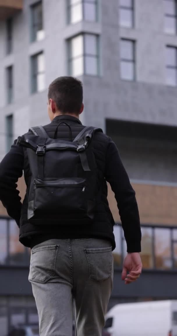 Hátsó nézet turista férfi séta a városban fekete hátizsák, függőleges videó — Stock videók