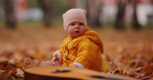 Liten bebis sitter vid höstparken — Stockvideo