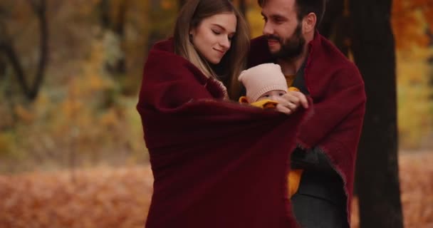 Feliz familia joven sosteniendo al pequeño bebé en el parque de otoño — Vídeos de Stock