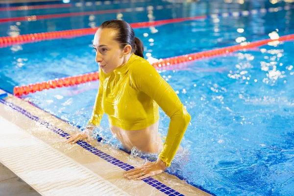 Mulher de biquíni amarelo emerge da piscina — Fotografia de Stock