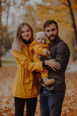 Sonbahar parkında mutlu genç aile portresi