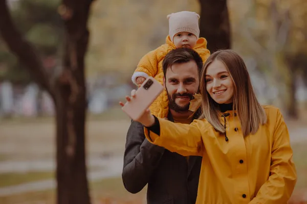 Retrato de família jovem feliz faz foto selfie no parque de outono — Fotografia de Stock