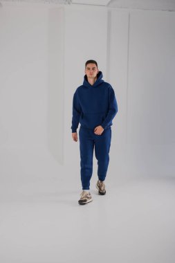 Stüdyoda mavi kapüşonlu kostüm giyen bir adam.