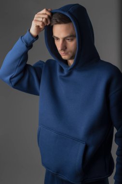 Stüdyoda mavi kapüşonlu kostüm giyen bir adam.