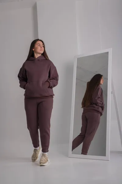 Woman posing in studio wearing brown hoodie costumes near mirror