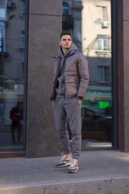 Şehirde ceketli bir adam poz veriyor.