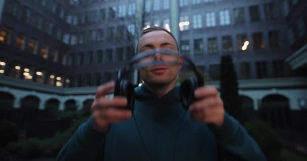 El hombre se pone auriculares en una ciudad en cámara lenta — Vídeo de stock