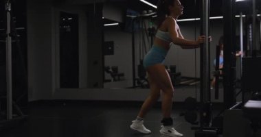 Kadın beden eğitimi aletleri üzerinde egzersiz yapıyor.