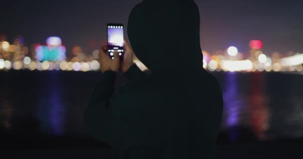 Молодой человек фотографирует городской пейзаж в сумерках — стоковое видео