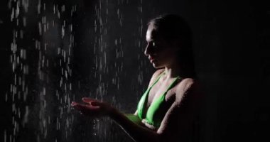 Bikinili kadın karanlıkta yağmur damlaları yakalıyor