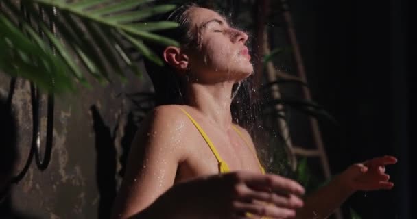 Krásná žena sedí v józe póza pod tropickou sprchou — Stock video