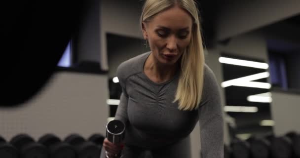 Подходящая женщина делает упражнения с гантелями в спортзале — стоковое видео